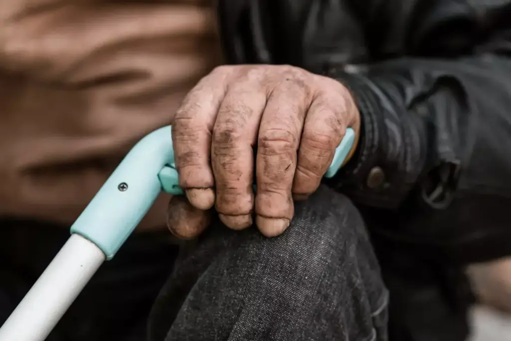 A close-up portrait of an elderly person's hands gripping a walking cane, expressing the physical discomfort and pain of arthritic joints. The hands are weathered and wrinkled, with visible swelling and redness around the knuckles. The cane casts a long shadow, emphasizing the weight and strain of the condition. The background is muted, with soft, diffused lighting that draws the viewer's focus to the hands. The overall mood is one of quiet contemplation and the need for effective relief from the debilitating effects of arthritis.
