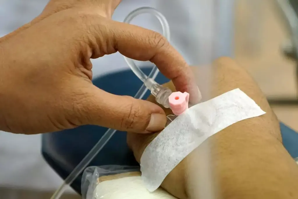 A detailed cross-section of a chemotherapy infusion process, with a central focus on the intravenous line delivering the cytotoxic medication. In the foreground, the patient's arm is gently resting, with the insertion point and tubing clearly visible. The middle ground features the infusion pump, its digital display and controls, conveying a sense of precision and monitoring. The background showcases the medical equipment and environment, such as an IV pole, medical cabinets, and subtle lighting that creates a calm, sterile atmosphere. The overall composition emphasizes the technical yet delicate nature of the chemotherapy administration, reflecting its vital role in cancer treatment. A detailed cross-section of a chemotherapy infusion process, with a central focus on the intravenous line delivering the cytotoxic medication. In the foreground, the patient's arm is gently resting, with the insertion point and tubing clearly visible. The middle ground features the infusion pump, its digital display and controls, conveying a sense of precision and monitoring. The background showcases the medical equipment and environment, such as an IV pole, medical cabinets, and subtle lighting that creates a calm, sterile atmosphere. The overall composition emphasizes the technical yet delicate nature of the chemotherapy administration, reflecting its vital role in cancer treatment.