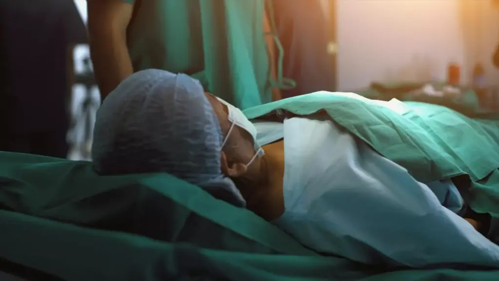 A disturbingly realistic scene of the final stages of metastatic brain cancer. In the foreground, a sickly, emaciated figure lies on a hospital bed, their head bandaged and tubes protruding from their arms. The middle ground reveals a blurred, desaturated medical environment, with a nurse tending to the patient with a somber expression. The background is shrouded in a haunting, muted darkness, symbolizing the overwhelming sense of impending mortality. Dim, moody lighting casts long shadows, creating a somber, melancholic atmosphere. The overall tone conveys the profound pain and suffering experienced during the final stages of this devastating disease.