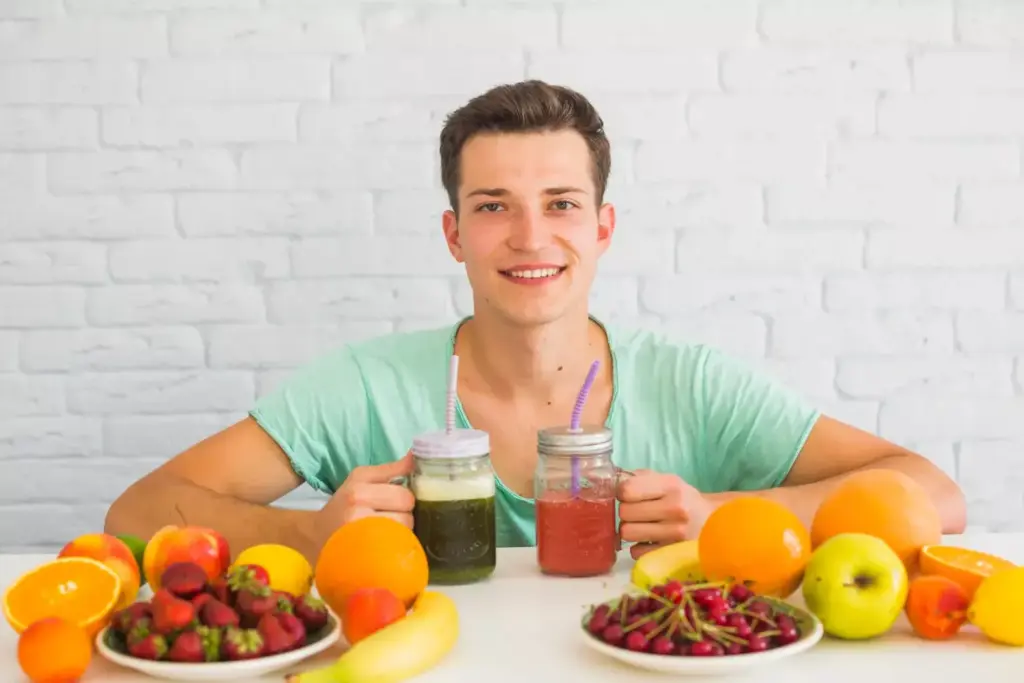 A man sitting at a table, leafing through a book about nutrition, with a glass of water and fresh fruits and vegetables surrounding him. The room is brightly lit with natural light from a large window, creating a warm and inviting atmosphere. The man's expression is thoughtful, as he considers the importance of proper nutrition for his recovery after prostate surgery. The image conveys a sense of care, diligence, and the patient's commitment to his health and well-being.