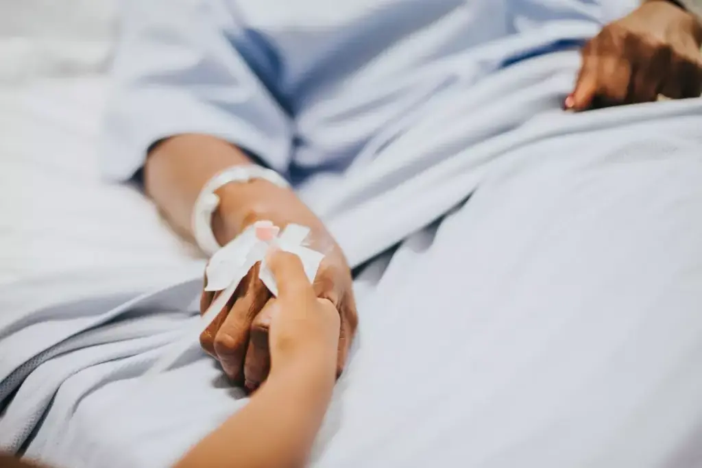 A patient's hand resting on a clean, white hospital bed, bandaged and elevated, with medical equipment such as an IV drip and monitoring devices visible in the foreground. The lighting is soft and diffused, creating a calming, clinical atmosphere. The middle ground shows a nurse's hands gently tending to the patient's wound, while the background features blurred medical personnel and supplies, suggesting the care and attention of the immediate post-surgery environment. A patient's hand resting on a clean, white hospital bed, bandaged and elevated, with medical equipment such as an IV drip and monitoring devices visible in the foreground. The lighting is soft and diffused, creating a calming, clinical atmosphere. The middle ground shows a nurse's hands gently tending to the patient's wound, while the background features blurred medical personnel and supplies, suggesting the care and attention of the immediate post-surgery environment.