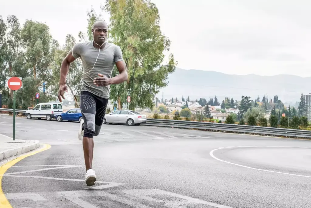 A person in athletic wear is running swiftly on a paved path through a serene park. The sun casts a warm, golden glow, illuminating the runner's determined expression and the lush, verdant surroundings. The scene conveys a sense of freedom, health, and the possibilities of returning to an active lifestyle after knee replacement surgery. The runner's stride is smooth and confident, suggesting the successful rehabilitation process. The composition places the runner in the middle ground, with a blurred but tranquil background of trees, benches, and other park elements, keeping the focus on the subject's progress. A person in athletic wear is running swiftly on a paved path through a serene park. The sun casts a warm, golden glow, illuminating the runner's determined expression and the lush, verdant surroundings. The scene conveys a sense of freedom, health, and the possibilities of returning to an active lifestyle after knee replacement surgery. The runner's stride is smooth and confident, suggesting the successful rehabilitation process. The composition places the runner in the middle ground, with a blurred but tranquil background of trees, benches, and other park elements, keeping the focus on the subject's progress.
