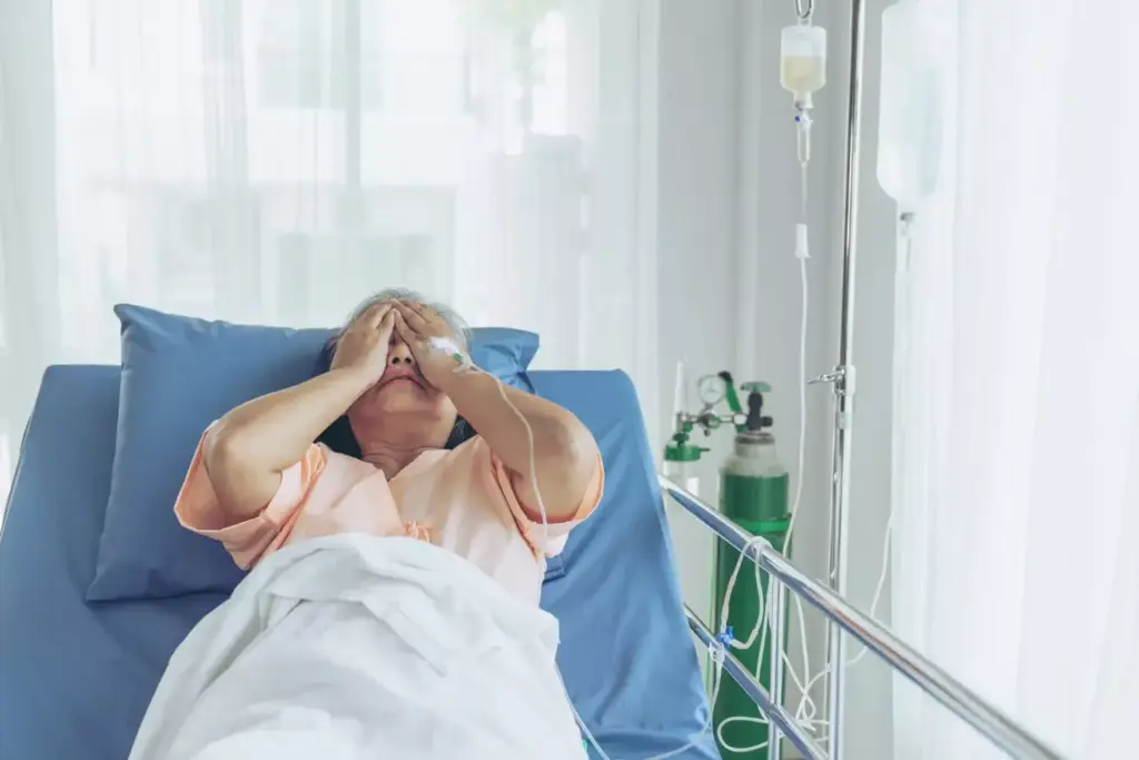 A person lying on a hospital bed, appearing exhausted and drained, with IV drips and medical equipment surrounding them. The background is a dimly lit hospital room, conveying a sense of weariness and the toll of chemotherapy treatment. Soft, diffuse lighting casts a somber, muted tone, emphasizing the patient's lack of energy. The composition focuses on the patient's face, displaying a pained expression and a faint, weary gaze, capturing the profound impact of chemotherapy on their energy levels.