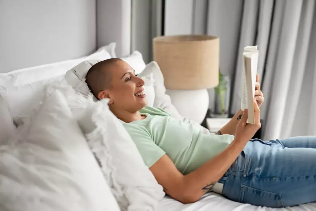 A person sitting on a sofa, resting and recovering from chemotherapy. The foreground shows a person wrapped in a soft, warm blanket, their face expressing a sense of relief and tranquility. The middle ground features a glass of water and a few small personal items nearby, suggesting a cozy, comfortable environment. The background is gently blurred, with muted colors and soft lighting, creating a serene and calming atmosphere. The overall scene conveys a sense of physical and emotional healing, with the person taking time to rest and restore their energy after the challenges of cancer treatment. A person sitting on a sofa, resting and recovering from chemotherapy. The foreground shows a person wrapped in a soft, warm blanket, their face expressing a sense of relief and tranquility. The middle ground features a glass of water and a few small personal items nearby, suggesting a cozy, comfortable environment. The background is gently blurred, with muted colors and soft lighting, creating a serene and calming atmosphere. The overall scene conveys a sense of physical and emotional healing, with the person taking time to rest and restore their energy after the challenges of cancer treatment.