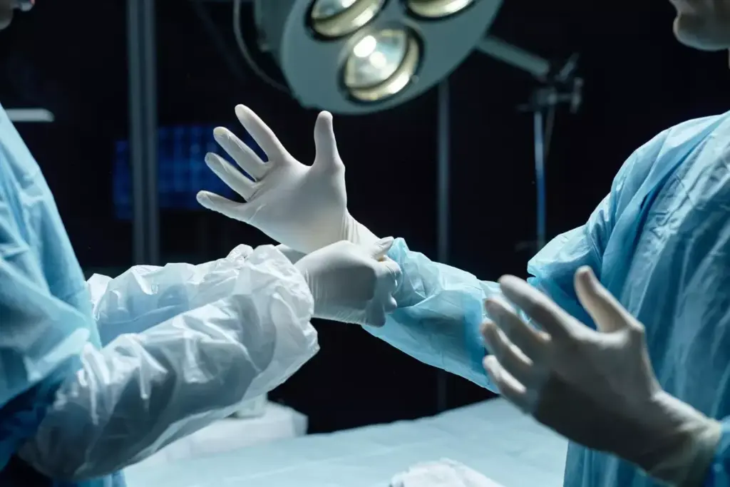 A surgical scene of a human hand undergoing carpal tunnel operation, with the palm facing upwards and fingers slightly spread. The incision site is clearly visible, surrounded by surgical tools such as scalpels, retractors, and sutures. The hand is bathed in a warm, sterile light, casting soft shadows that accentuate the anatomical details. The background is blurred, maintaining focus on the intricate procedure taking place. The overall atmosphere conveys a sense of medical expertise, precision, and the necessity of this delicate operation.