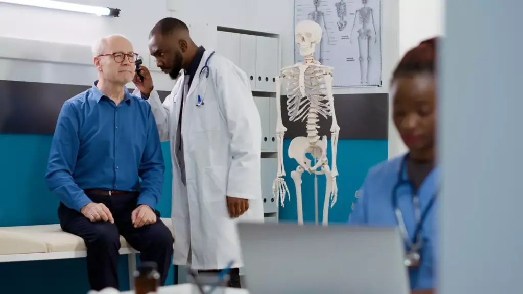A well-lit, detailed medical illustration depicting a patient undergoing preoperative evaluation for 360 fusion surgery. The subject is a middle-aged person lying on an examination table, with a doctor or surgeon examining their spine. The background shows a dimly lit, sterile medical setting with diagnostic imaging such as X-rays or MRI scans displayed on a nearby monitor. The image conveys a sense of clinical professionalism and the careful patient selection process required for this complex spinal procedure.