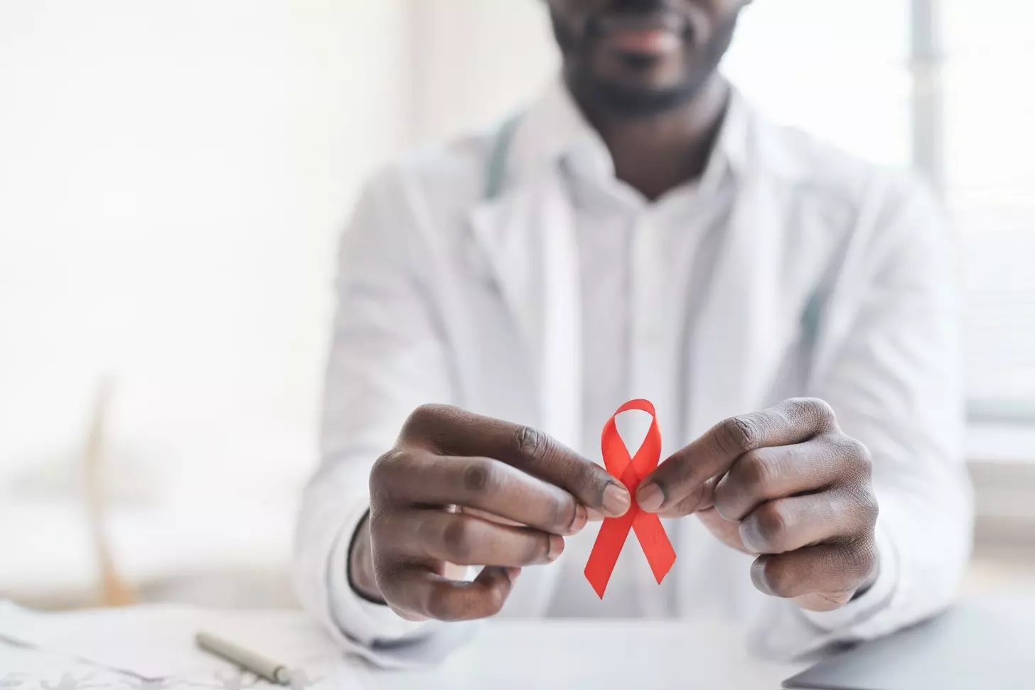 African doctor holding red ribbon in his hands at hospital