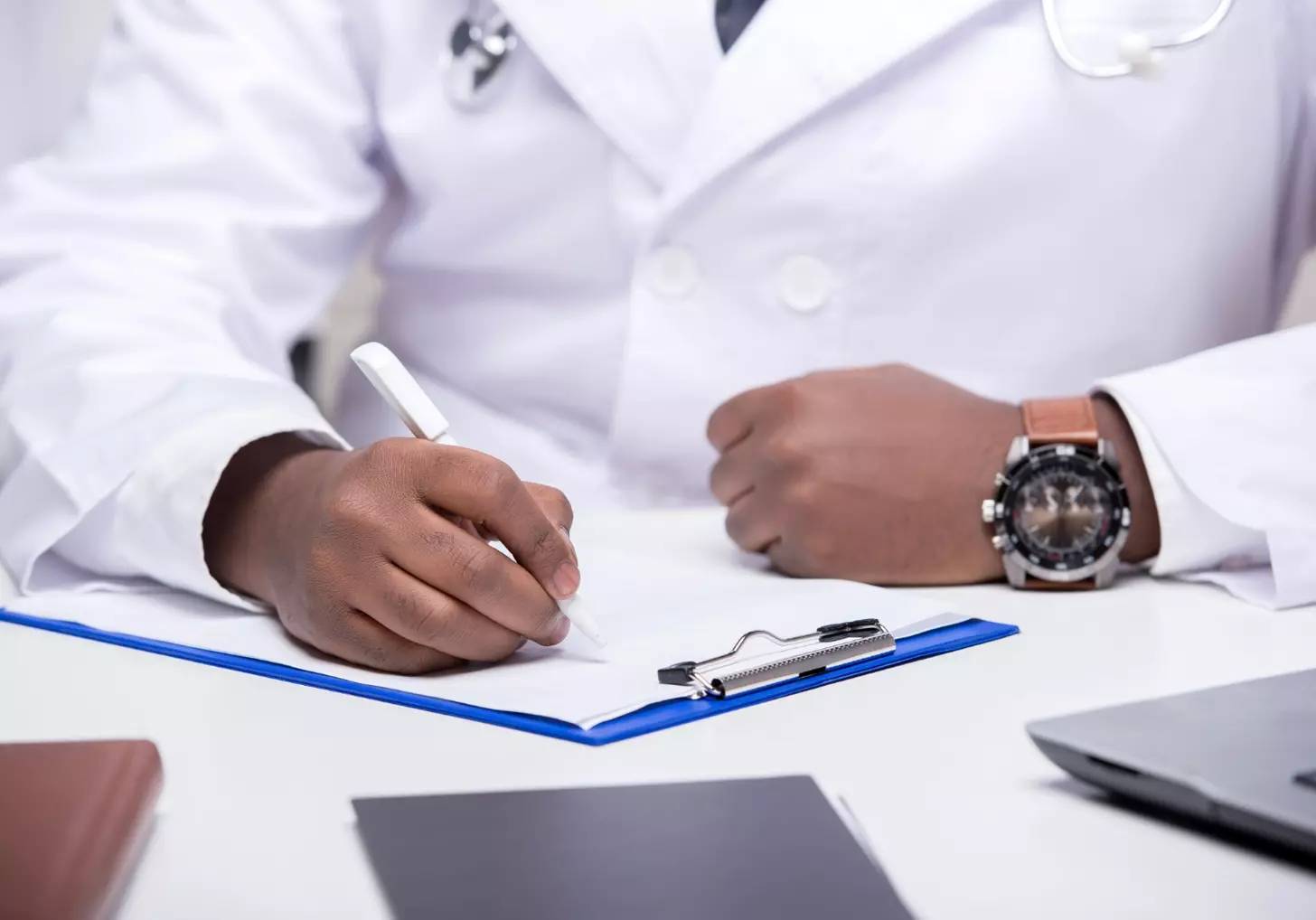 Close-up hands of african doctor is sitting at table.