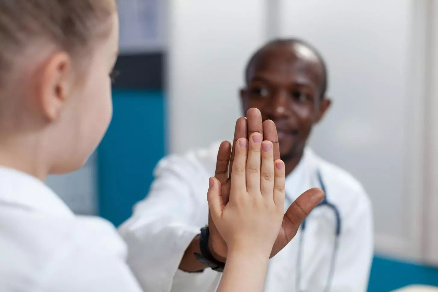 Closeup of african american pediatrician doctor giving high five to young girl