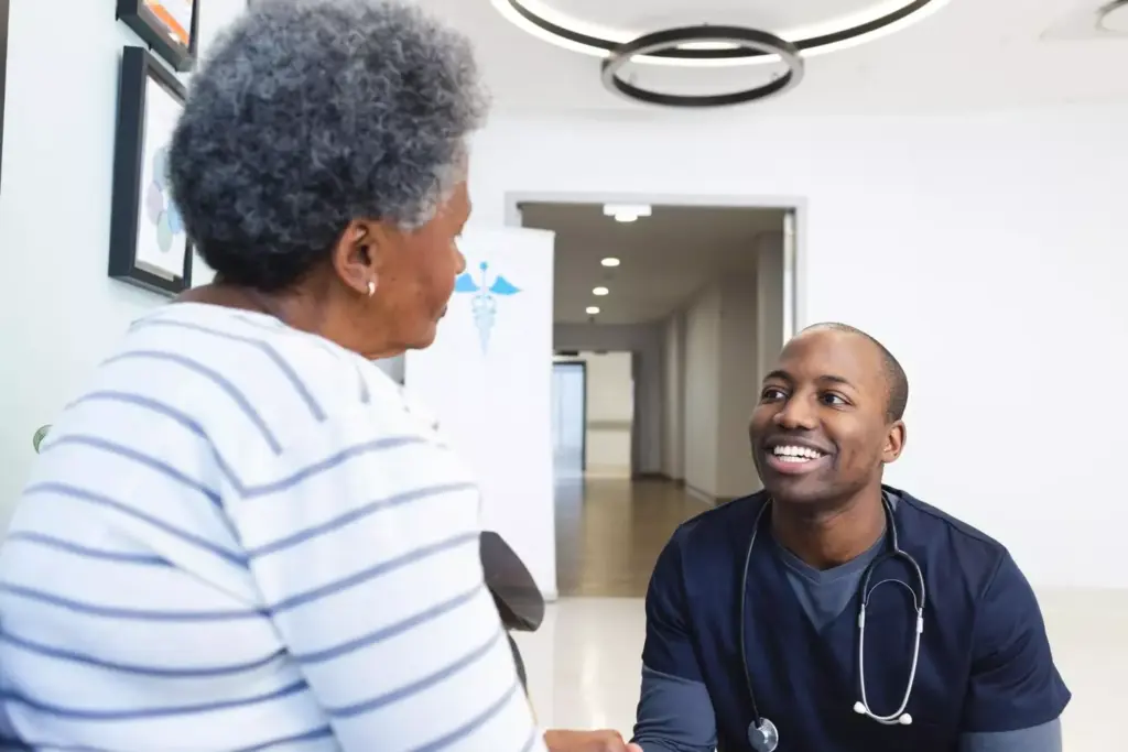Happy african american male doctor talking with senior woman in hospital