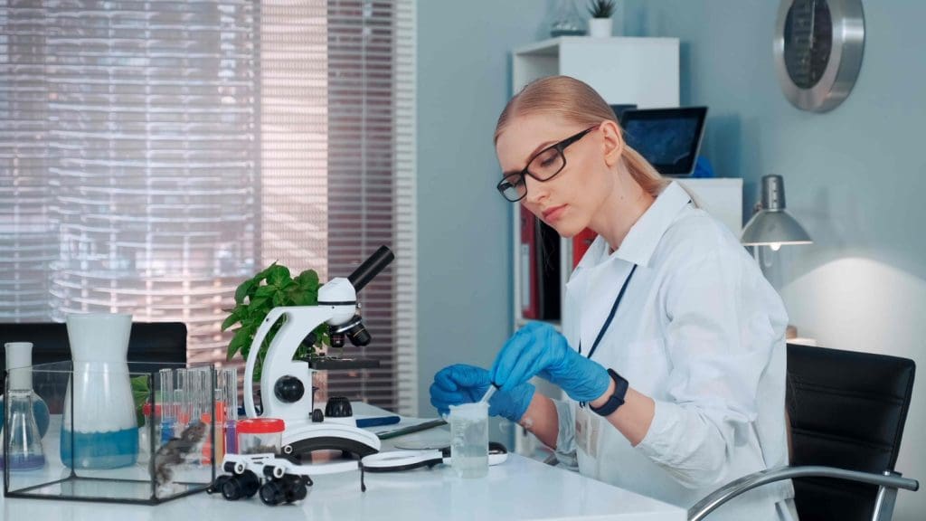  clinical laboratory setting with a scientist in a white coat examining a sample under a microscope